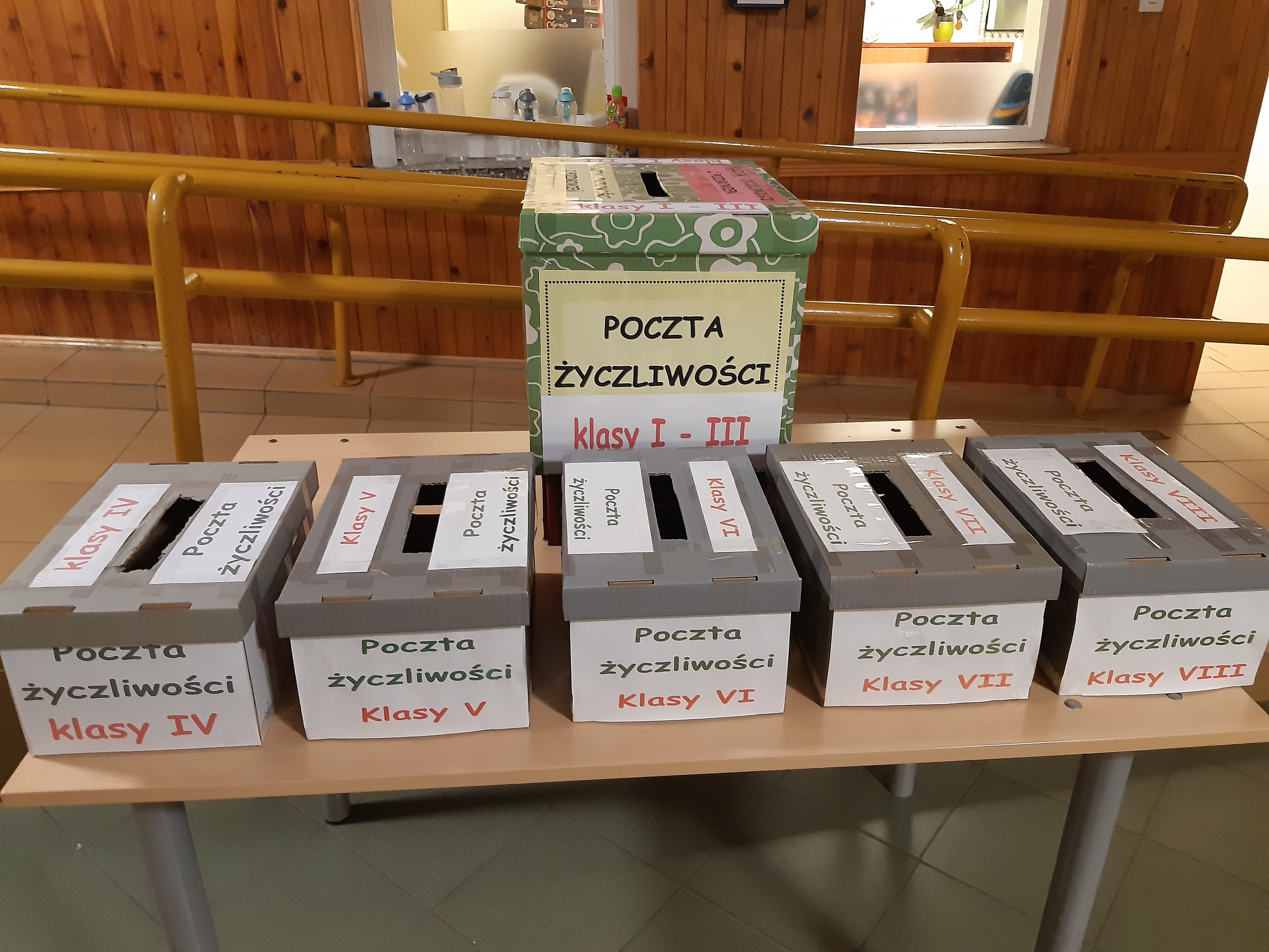 skrzynki życzliwości ustawine na ławce pry wejściu do szkoły