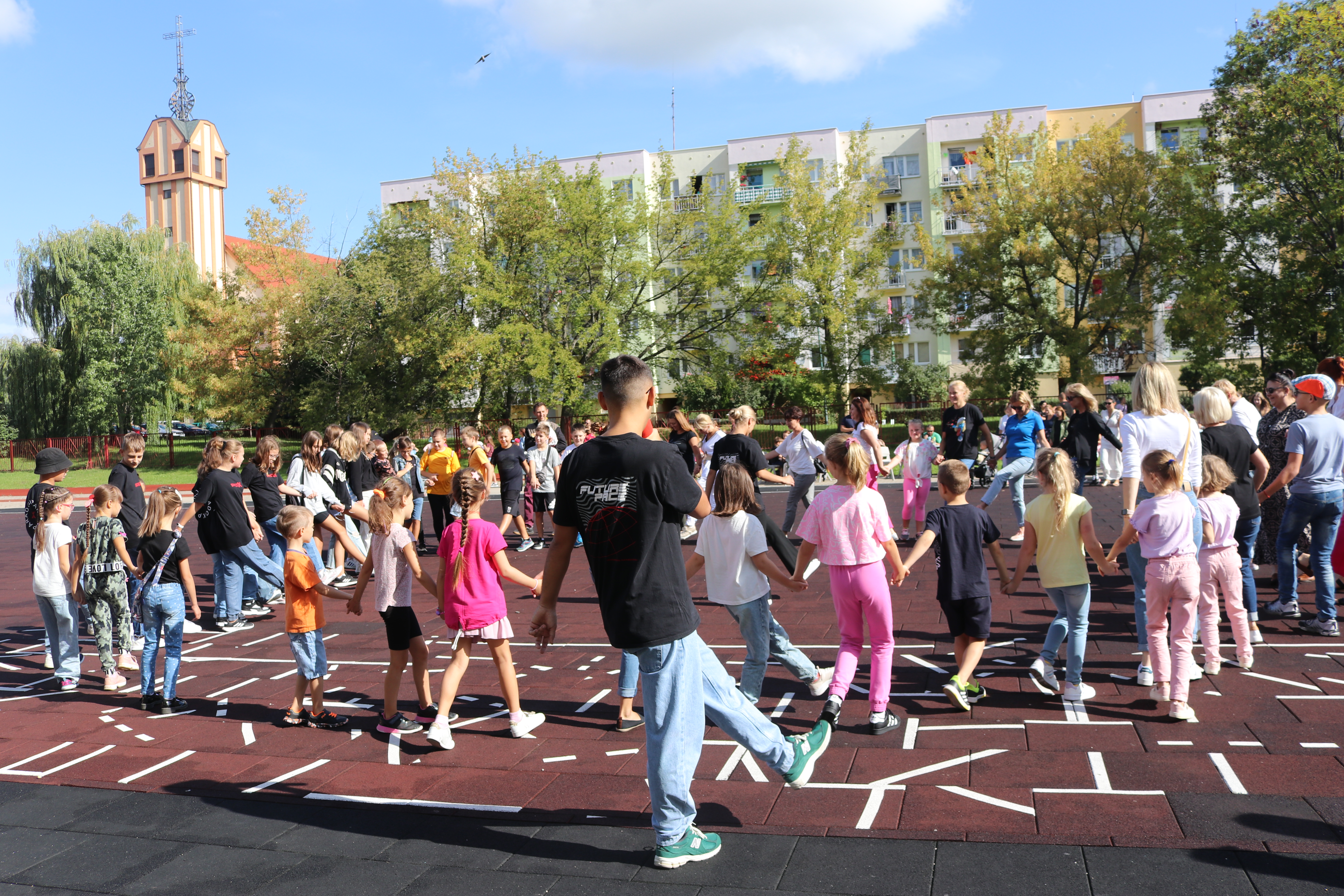 Uczniowie tańczą na boisku szolnym na festynie rodzinnym.